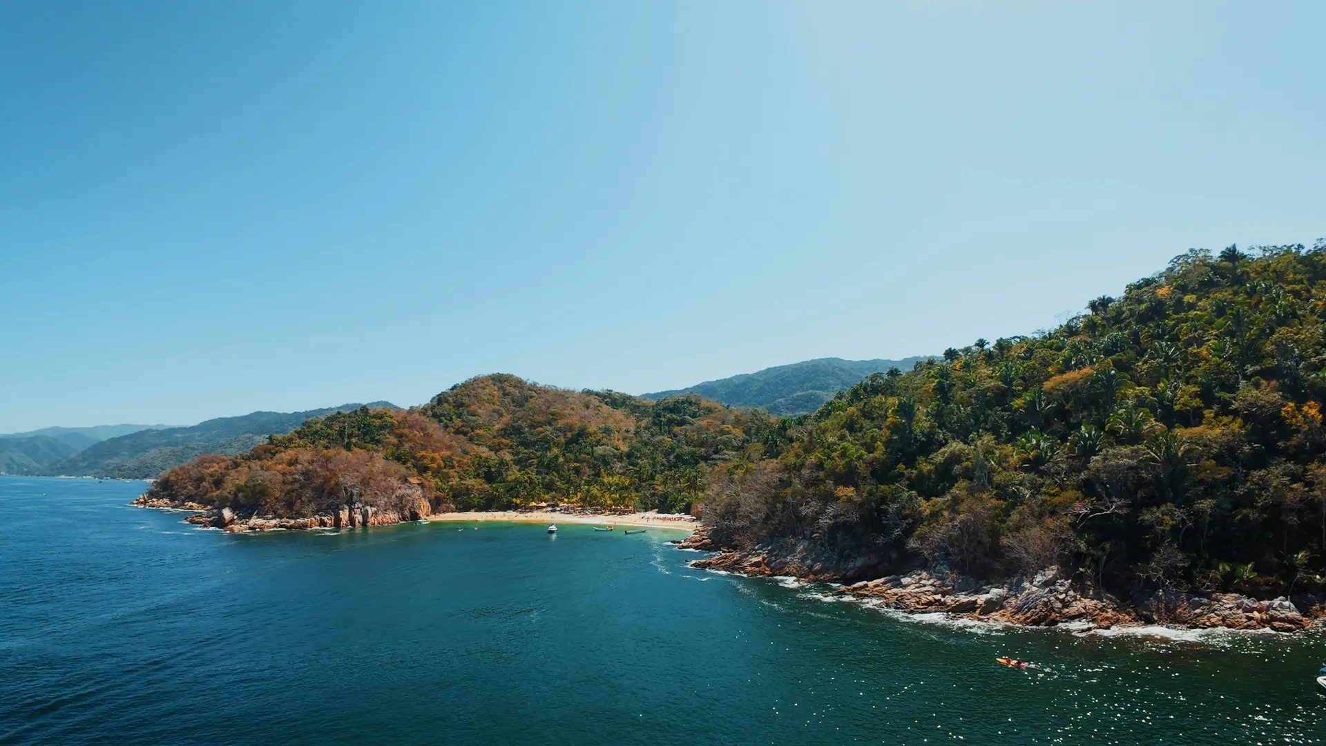 Majahuitas beach seen from the water: a small sandy cove backed by jungle hills south of Puerto Vallarta