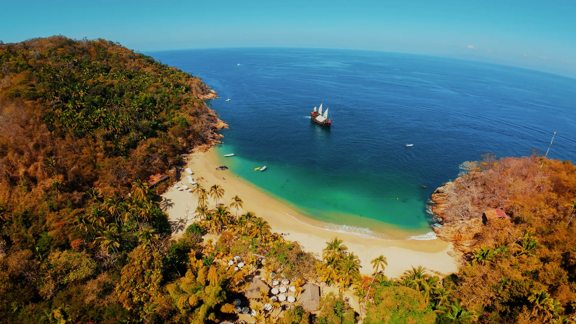 Aerial view of the pirate ship anchored off Majahuitas beach, a palm-lined cove with turquoise water