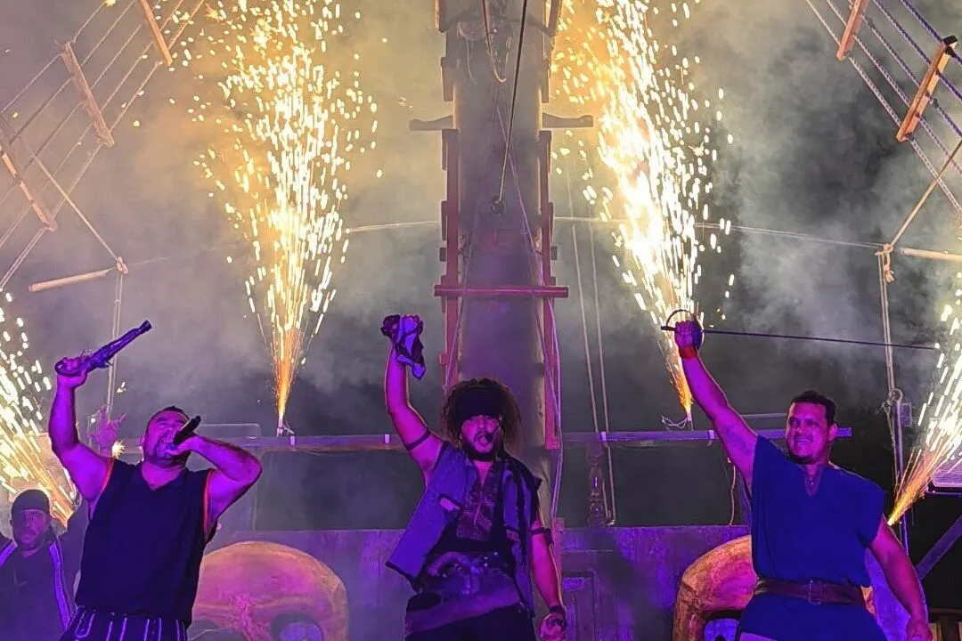 Pirate performers raise a pistol and sword as sparkler fountains go off during the night show