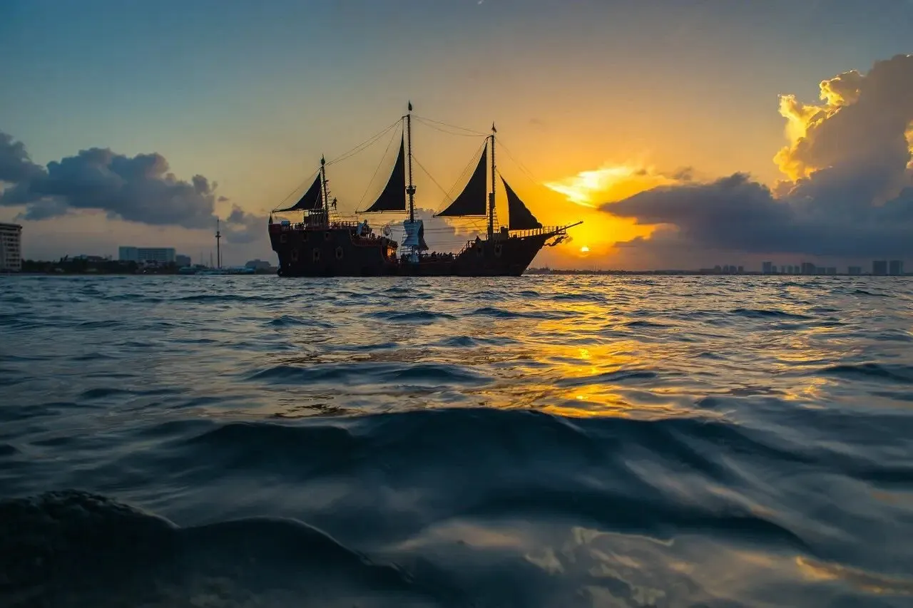 The Puerto Vallarta pirate ship silhouetted against the setting sun, seen from water level